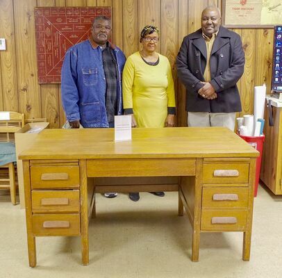 Kane School Graduates Bruce Perry, Martha Holbrook, and Howard Dillard stand behind the desk of their former teacher Mrs. Cole. The three remembered students having to sit under the desk when they misbehaved. The desk was donated to the Hickman County Historical Society by Joe and Denise Terry. (Photo by Becky Meadows)