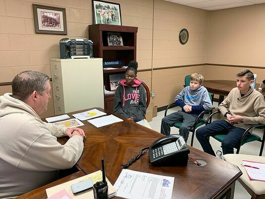 LEARNING IMPORTANCE OF HOUSE NUMBERS – Fulton County Middle School’s Young Leaders in Action talk with Fulton County Sheriff Derek Goodson about the importance of house numbers. The Young Leaders are working to have home owners place 3 – 6 inch numbers on houses to help emergency personnel find homes while responding to a call. Pictured, from left, Sheriff Goodson, A’Maareese Esters, Logan Griffiths and Daniel Collins. Connor O’Malley is not pictured. (Photo submitted)