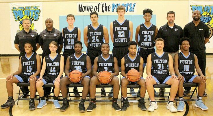2018-19 PILOTS – The Fulton County Pilots 2018-19 basketball team members are, front row, left to right, DiAvian Bradley, Issac Madding, Jerome Warren, Caleb Kimble, Kahari Miller, Cameron Cole, Armani Yandal; back row, Head Coach Jamie Madding, Assistant Coach Corey Smith, Hayden Murphy, Dylan Hammond, Camden Aldridge, George Scott, Assistant Coach Jason Sipes, and Assistant Coach Craig Clay. (Photo by Charles Choate)