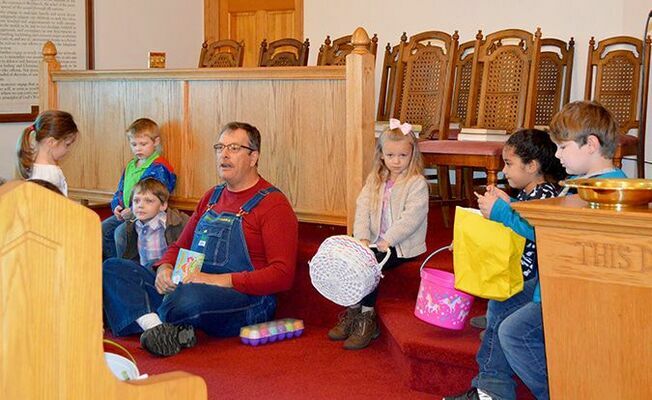 RESURRECTION STORY TIME – Brother Mark Dowdy sits in the floor with children attending Cayce Baptist Church’s Easter Egg Hunt April 20. Bro. Dowdy is telling the Resurrection Story with a set of eggs, each containing an item relating to the last week of Jesus’ life. Children attending enjoyed the story, refreshments, and the egg hunt. (Photo by Barbara Atwill)