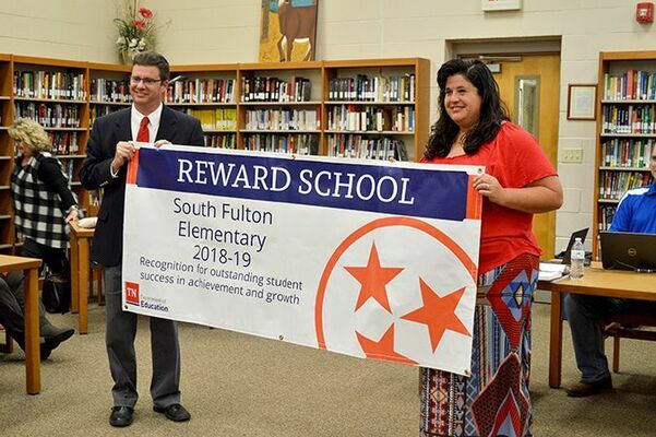 Tim Watkins, Director of Schools for Obion County’s system, presented South Fulton Elementary Principal Laura Pitts with a banner for display honoring SFES as a ‘Reward School’. (Photo by Benita Fuzzell)