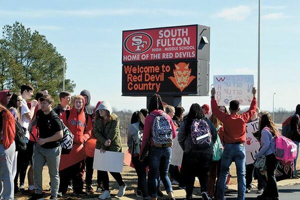 DELIVERING DEVIL PRIDE, IN THIS PHOTO PUBLISHED IN THE CURRENT FEB. 13 – South Fulton Middle and High School students, along with faculty and administrators, lined the drive along the entrance to the SFMS/HS campus Feb. 8, to support the South Fulton Middle School Lady Red Devils basketball team as they departed South Fulton for the first Tennessee Middle School Athletic Association state basketball tournament. The Lady Devils earned their position in the state level bracket by defeating Obion County’s Hillcrest team. Well-wishers lined up along the four-lane between the Middle/High School and South Fulton Elementary campuses cheering on the team bus, with SFES students lined up outside their school to show support. (Photo by Benita Fuzzell.)